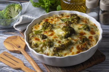 Casserole Cauliflower and broccoli baked with cheese sauce in a pot close-up on a wooden table. Horizontal top view from above. Broccoli gratin.