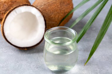 Bir şişe hindistan cevizi yağı ve palmiye yapraklı taze hindistan cevizi.