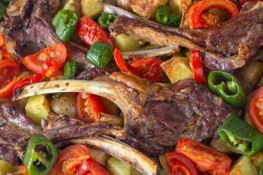 Fırında kuzu pirzolası ve patates gibi sotelenmiş sebzeler.