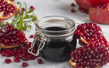 Glass bottle of pomegranate sour sauce with fresh ripe whole and split pomegranate fruit (Turkish name; nar eksisi)