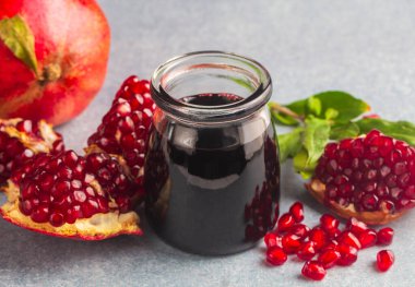 Glass bottle of pomegranate sour sauce with fresh ripe whole and split pomegranate fruit (Turkish name; nar eksisi)