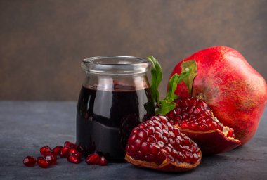 Glass bottle of pomegranate sour sauce with fresh ripe whole and split pomegranate fruit (Turkish name; nar eksisi)