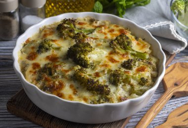 Casserole Cauliflower and broccoli baked with cheese sauce in a pot close-up on a wooden table. Horizontal top view from above. Broccoli gratin.