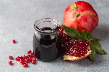 Glass bottle of pomegranate sour sauce with fresh ripe whole and split pomegranate fruit (Turkish name; nar eksisi)