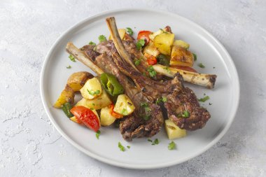 Fırında kuzu pirzolası ve patates gibi sotelenmiş sebzeler. 