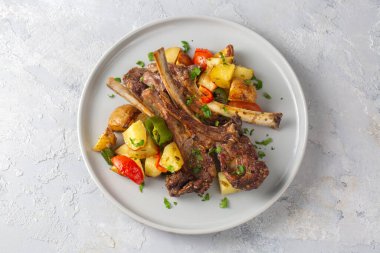 Fırında kuzu pirzolası ve patates gibi sotelenmiş sebzeler. 