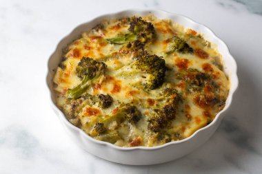 Casserole Cauliflower and broccoli baked with cheese sauce in a pot close-up on a wooden table. Horizontal top view from above. Broccoli gratin.
