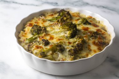 Casserole Cauliflower and broccoli baked with cheese sauce in a pot close-up on a wooden table. Horizontal top view from above. Broccoli gratin.