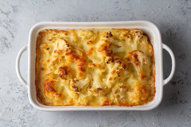 Karnabahar güveci, ahşap bir masada, yakın plan bir kapta peynir sosuyla pişirilmiş. Yukarıdan yatay üst görünüm. Karnabahar graten