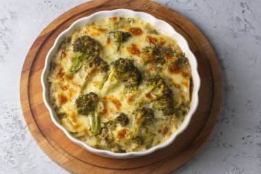 Casserole Cauliflower and broccoli baked with cheese sauce in a pot close-up on a wooden table. Horizontal top view from above. Broccoli gratin.