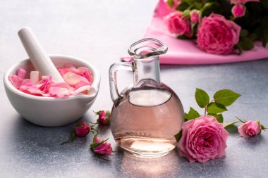 Bir şişe gül yağı ve çiçek.