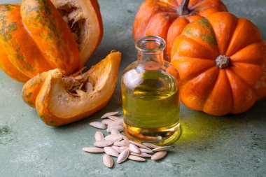 Sağlıklı kabak çekirdekleri yağ şişesi, ahşap mutfak masasında balkabakları..
