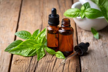 Fesleğen yağı ve taze yapraklar ahşap masada, yakın plan.