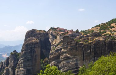 Yunanistan 'ın Meteora kentinin havadan görünüşü, dramatik bulutlu gökyüzünün altında yükselen kayaların üzerinde bulunan ve yemyeşil manzaralarla çevrili antik manastırlara ev sahipliği yapıyor..