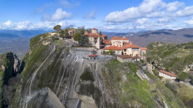 Yunanistan 'ın Meteora kentinin havadan görünüşü, dramatik bulutlu gökyüzünün altında yükselen kayaların üzerinde bulunan ve yemyeşil manzaralarla çevrili antik manastırlara ev sahipliği yapıyor..