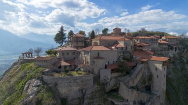 Yunanistan 'ın Meteora kentinin havadan görünüşü, dramatik bulutlu gökyüzünün altında yükselen kayaların üzerinde bulunan ve yemyeşil manzaralarla çevrili antik manastırlara ev sahipliği yapıyor..