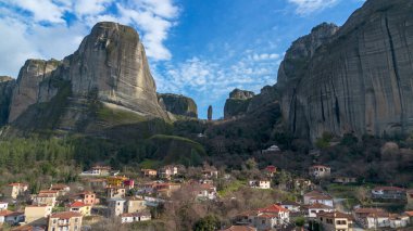 Yunanistan 'ın Meteora kentinin havadan görünüşü, dramatik bulutlu gökyüzünün altında yükselen kayaların üzerinde bulunan ve yemyeşil manzaralarla çevrili antik manastırlara ev sahipliği yapıyor..
