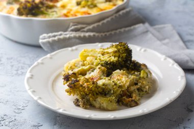 Casserole Cauliflower and broccoli baked with cheese sauce in a pot close-up on a wooden table. Horizontal top view from above. Broccoli gratin.