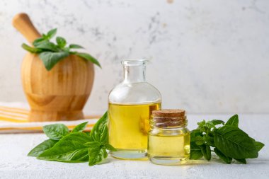 Fesleğen yağı ve taze yapraklar ahşap masada, yakın plan.