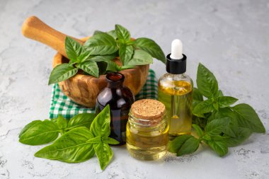 Fesleğen yağı ve taze yapraklar ahşap masada, yakın plan.