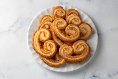 Beyaz arka planda karamelize katmanlı altın palmiyeli poğaça kurabiyeleri, fırın markaları veya yemek görselleri için mükemmel..