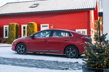 Tnsberg, Norveç - 2 Aralık 2023: Norveç evinin yanında turuncu kırmızı Hyundai Ioniq elektrikli araba şarj ediliyor