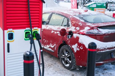 Tonsberg, Norveç - 27 Aralık 2023: turuncu kırmızı Hyundai Ioniq elektrikli araba şarj istasyonunun yanında