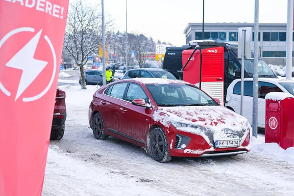 Tonsberg, Norveç - 27 Aralık 2023: turuncu kırmızı Hyundai Ioniq elektrikli araba şarj istasyonunun yanında