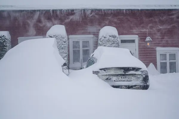 ノルウェーのトンズバーグ 2024年1月1日 オレンジ色の赤いヒュンダイ イオニクの電気自動車が雪の下に降りました スノーストーム 雪の送風機で雪を除去する ロイヤリティフリーのストック画像