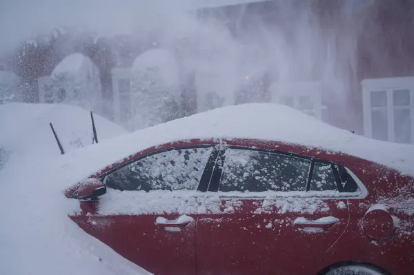 ノルウェーのトンズバーグ 2024年1月1日 オレンジ色の赤いヒュンダイ イオニクの電気自動車が雪の下に降りました スノーストーム 雪の送風機で雪を除去する ロイヤリティフリーのストック写真