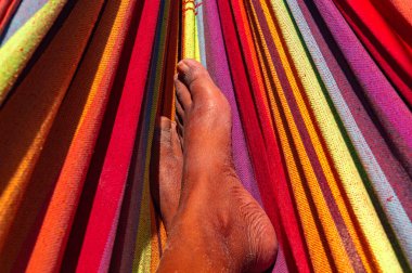 Canlı ve göz alıcı bir hamakta dinlenen renkli bir insanın ayaklarına odaklanan yakın çekim görüntüsü..