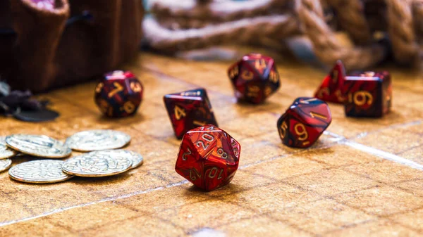 Düşük açılı çekim, savaş haritasında düzenlenmiş canlı kırmızı RPG zarları ve altın oyun paraları koleksiyonu içerir.