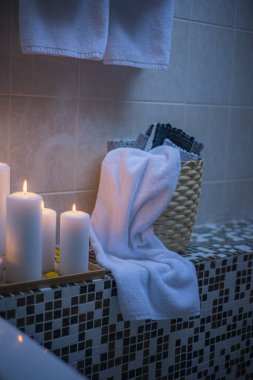 Banyodaki hasır poşette bükülmüş beyaz havlular, mumlu banyo havluları, spa ve aşk konsepti.