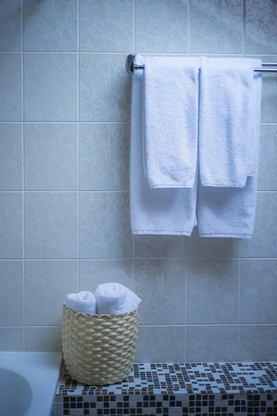 hanging white towels in bathroom, bath towels in white tiled bathroom, home spa and cleanliness concept