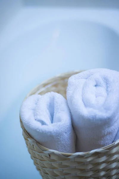 twisted white towels in a wicker bag in the bathroom, twisted bath towels in a basket, the concept of home comfort and coziness