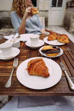 beautiful french breakfast, croissant and Madeleines served on a wooden table, woman on the background clipart