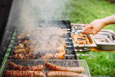 Sosis ve şiş kebap, ızgarada şiş kebap, tavuk ve domuz barbeküsü, el ele tutuşmak, yatay.