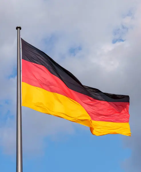 The German flag flying from a flagpole flapping in the wind