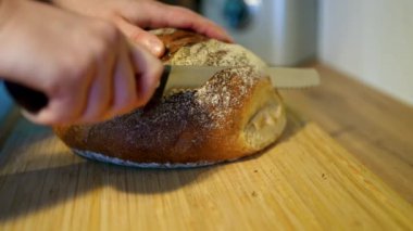 Zanaatkar ekmeği güzel bir şekilde sade ahşap bir tahtanın üzerinde dizilmiş, çekici dokusunu ve kabuğunu sergiliyor.