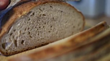 Zanaatkar ekmeği güzel bir şekilde sade ahşap bir tahtanın üzerinde dizilmiş, çekici dokusunu ve kabuğunu sergiliyor.