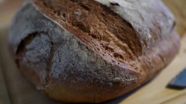 Kaba bir zanaatkar ekmeği ahşap bir kesme tahtasının üzerinde zarif bir şekilde sunulur.