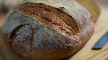 Kaba bir zanaatkar ekmeği ahşap bir kesme tahtasının üzerinde zarif bir şekilde sunulur.