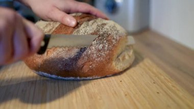 Zanaatkar ekmeği güzel bir şekilde sade ahşap bir tahtanın üzerinde dizilmiş, çekici dokusunu ve kabuğunu sergiliyor.