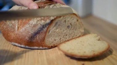 Zanaatkar ekmeği güzel bir şekilde sade ahşap bir tahtanın üzerinde dizilmiş, çekici dokusunu ve kabuğunu sergiliyor.