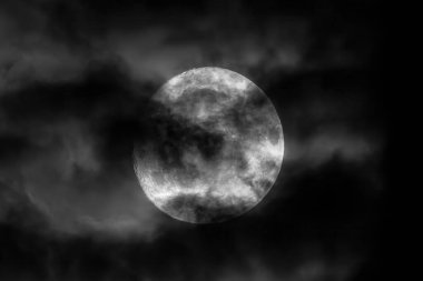 A captivating blackandwhite image of a glowing, luminous moon that is partially obscured by soft, wispy clouds clipart