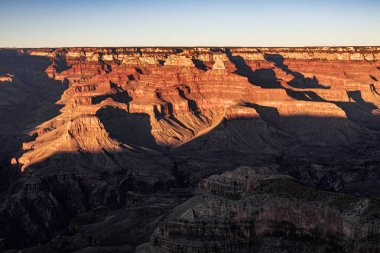 Açık mavi gökyüzünün altında uzanan nefes kesici ve şaşırtıcı güzellikteki engebeli kanyon manzarasını keşfedin.