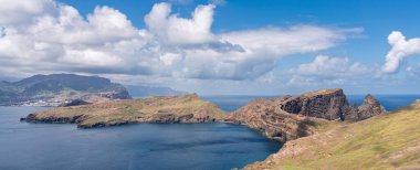 Ponta de Sao Lourencos 'un Atlantik Okyanusu' yla buluşan engebeli uçurumlarının nefes kesici manzarası. Dağınık bulutlu açık gökyüzü Madeira 'ya dokunulmamış kıyı güzelliği, doğa ve seyahat temaları için ideal.