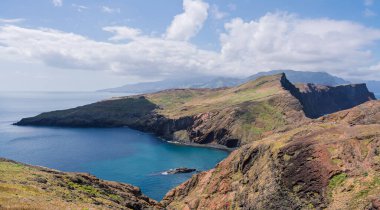 Ponta de Sao Lourencos 'un Atlantik Okyanusu' yla buluşan engebeli uçurumlarının nefes kesici manzarası. Dağınık bulutlu açık gökyüzü Madeira 'ya dokunulmamış kıyı güzelliği, doğa ve seyahat temaları için ideal.