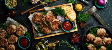 Bir set kızarmış et, pirzola ve şiş kebap, el yapımı tarif. Siyah taştan bir arka planda. Üst görünüm.