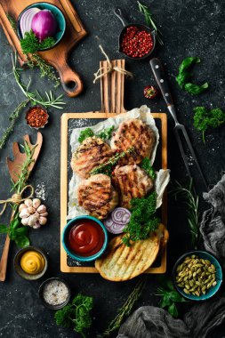 Barbekü: domuz pastırması ve soslu ızgara köfte. Taş bir tahtanın üzerinde. Üst görünüm.